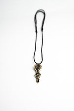 Artistic shot of the biomechanical pendant laying on a white background, emphasizing its sculptural and industrial style