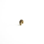 A side-angle view of a brass bio-organic septum ring with a clicker closure, showing its smooth curvature and antique finish.