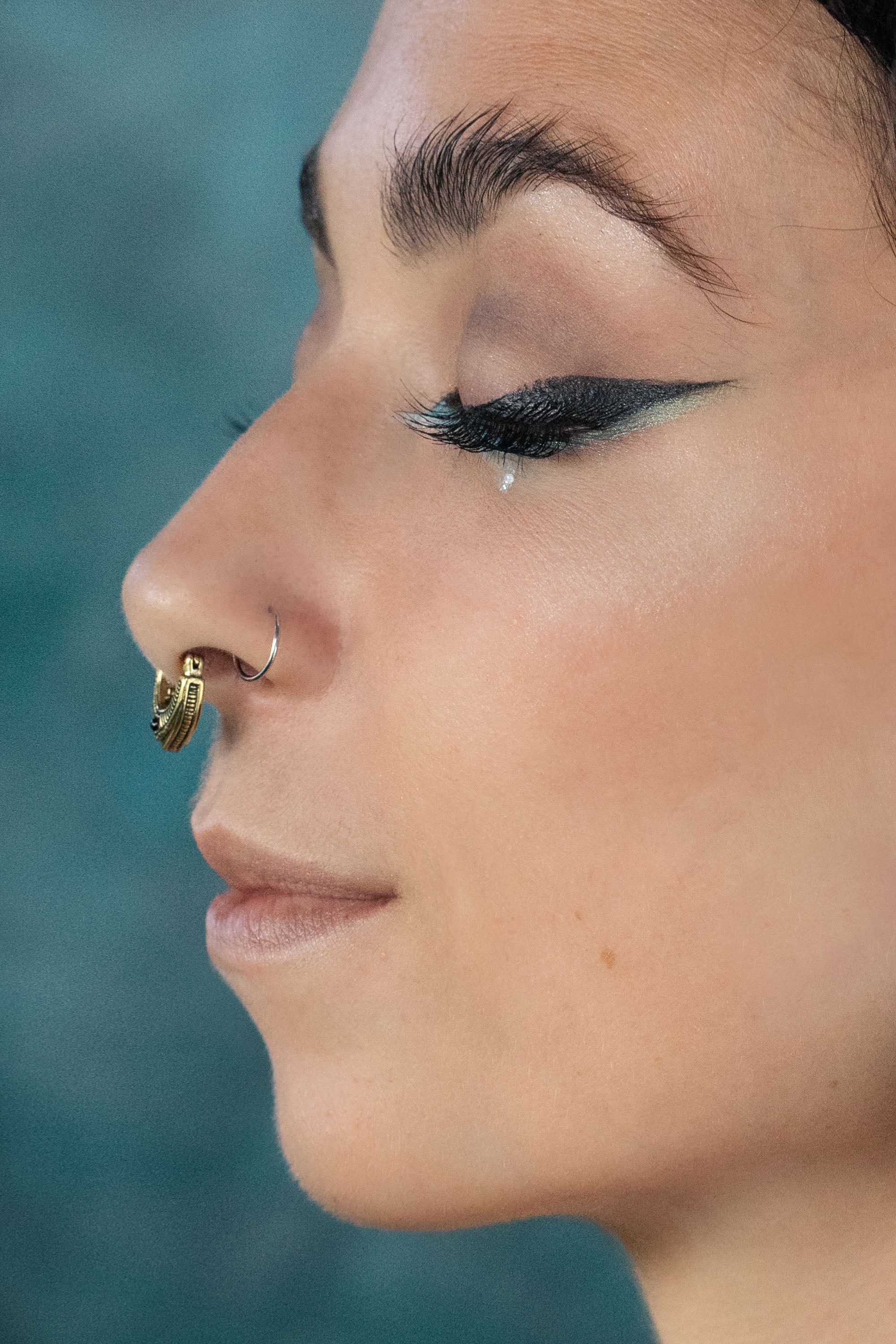 Close up artistic shoot of a women wearing a gold septum clicker with garnet stone