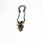 Close-up of the brass spoon pendant, highlighting its biomechanical details and the smooth, polished finish.