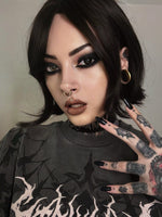 Side profile of a tattooed model wearing a biomechanical gold septum clicker and stretched ear plugs. Her piercing gaze and gothic-inspired attire enhance the post-apocalyptic fashion look.