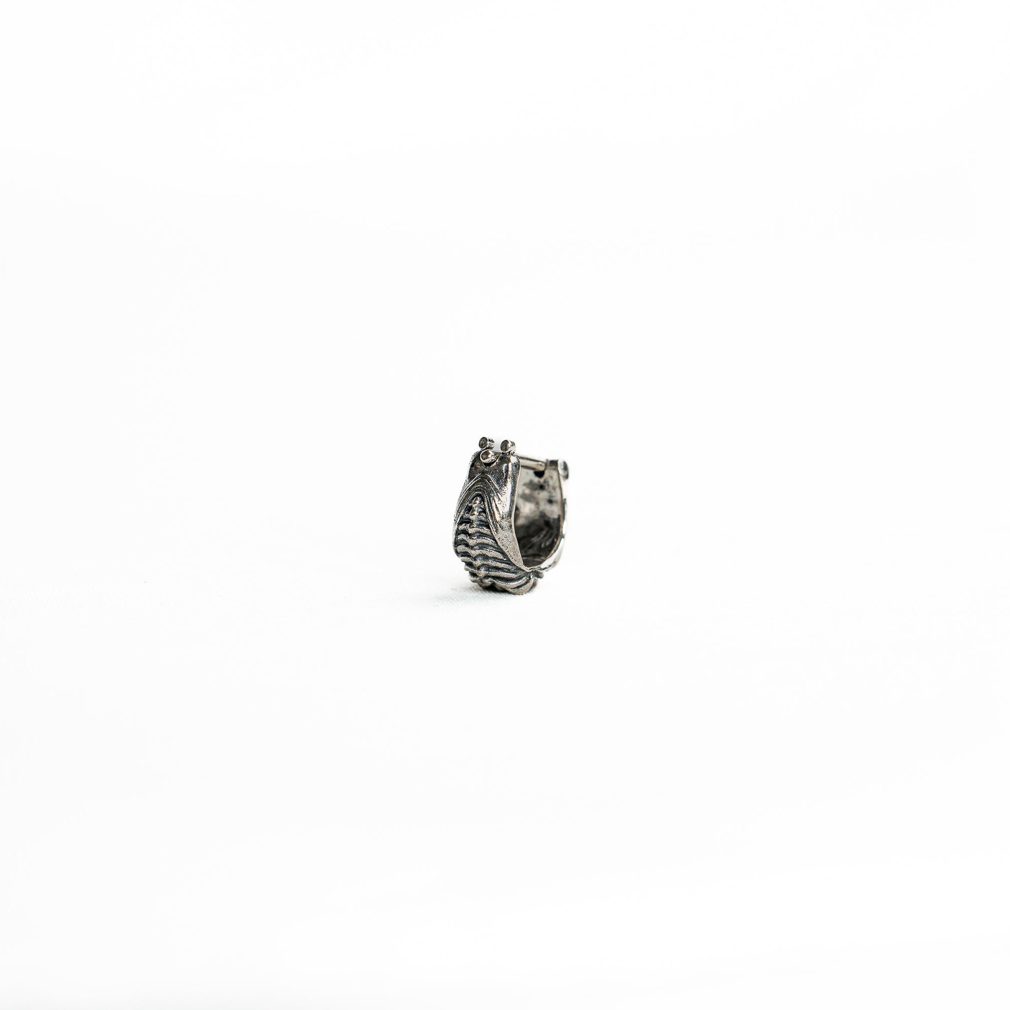 A close-up of a Silver 925 bioorganic septum clicker, featuring an intricate biomechanical-inspired design with a secure clicker closure, displayed on a clean white background.