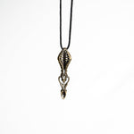 Brass biomechanical pendant with a ribbed exoskeleton design, inspired by futuristic and gothic aesthetics, suspended on a black cord.