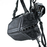 Close-up photo of a pair of black leather handbags. The KERO Unisex Lightweight Leather Holster Bag by Kaya Movement features stitched and textured detailed panels with small rivets, exuding a post-apocalyptic harness bag vibe. The other bag has a zippered compartment and braided straps. Both bags are adorned with metal hardware for a rugged look.