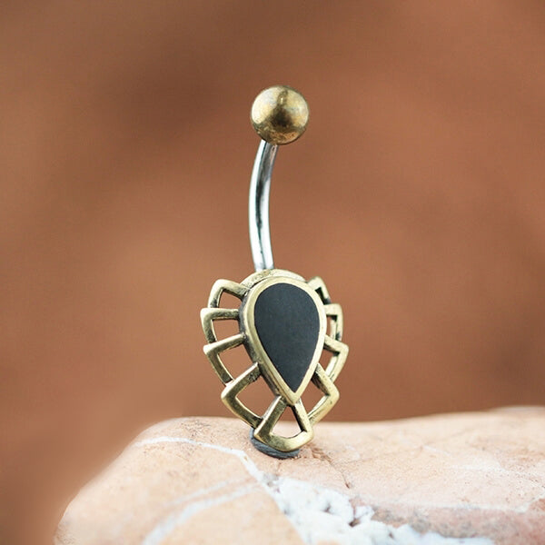 A close-up image showcasing the refined OSALI Marquise Belly Piercing Ring in Gold & Black Pearl by Kaya Movement. This elegant piece displays a gold frame with a Black Mother Pearl center, set on a surgical steel curved barbell and accentuated by a rounded ball at the top end. The soft, muted brown background enhances its luxurious design.