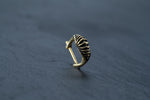 A close-up image of the DIARA Biomechanical Clicker Hoop Septum Nose Ring in Gold by Kaya Movement showcases its intricate, ribbed design and polished finish, set against a dark, textured background.