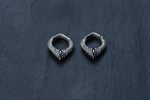A pair of intricately designed MARVDASHT Small Biomechanical Clicker Ear Weights in 925 Silver by Kaya Movement, featuring curved, snake-like bodies and scale patterns, are displayed on a dark, textured background. These unisex 2 gauge earrings exude subtle sci-fi vibes.