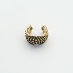 A close-up view of the DARMA Fake Septum Ring or Ear Cuff in Gold by Kaya Movement. This intricately designed, open-ended piece features a series of evenly spaced vertical lines and an elaborate pattern, giving it a vintage or antique appearance. This versatile unisex jewelry is set against a plain, light background.