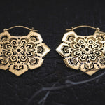 The ASA Oversized Asa No Ha Mandala Disc Earrings in Gold from Kaya Movement are intricately designed and displayed on a dark, textured background. These 16-gauge ethnic statement earrings showcase a geometric and floral-inspired pattern with delicate cutouts, creating a lacy, mandala-like appearance.