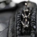 Close-up image of the black leather zipper on the APOPHIS Post-Apocalyptic Leather Shoulder & Belt Bag by Kaya Movement, highlighting the shiny silver zipper teeth in sharp detail. The leather appears textured and soft, with a focus on the center part of the zipper against a blurred background.