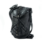 A black APOPHIS Post-Apocalyptic Leather Shoulder & Belt Bag by Kaya Movement is shown. This leather crossbody bag showcases intricate designs and multiple textures, including fabric, along with decorative elements like studs, zippers, and braided details. Its unique, edgy style and compact rectangular shape make it the perfect accessory for a wasteland festival.