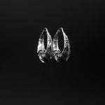 A close-up image of the PROMETHEUS Medium Biomechanical Hoop Earrings in 925 Silver from Kaya Movement against a black background. These unisex earrings showcase an intricate, metallic design with sharp angles and interweaving sections, blending modern and ancient styles—ideal as sci-fi statement pieces.