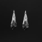 A pair of PROMETHEUS Medium Biomechanical Hoop Earrings in 925 Silver by Kaya Movement, displayed against a black background. The elongated teardrop shapes boast intricate designs and small circular indentations, lending them a rustic, handmade appearance. These 18-gauge sci-fi statement earrings evoke a post-apocalyptic sense of style.