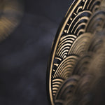 Close-up of the SEIGAIHA Oversized Japanese Geometry Disc Earrings in Gold by Kaya Movement, intricately designed with an overlapping, semi-circular, wave-like pattern. The metallic texture and boho elements are emphasized by the blurred background, showcasing the detailed craftsmanship of these unisex statement earrings at 16 gauge.