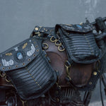 A close-up of a motorcycle adorned with two vintage-style SHIPIBO Tribal Apocalyptic Leather Belt & Shoulder Bags from Kaya Movement. Each bag features a studded design and decorative patches. The weathered bike, evoking scenes from dystopian festivals, shows visible rust and an old-fashioned structure that tells stories of its travels.