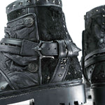 Close-up of stylish MAGMA Wasteland Studded Leather Ankle Combat Boots by Kaya Movement, featuring buckle straps and metal studs that showcase their intricate texture and rugged design. These boots have a thick sole and detailed stitching, adding to their edgy and contemporary look.