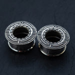 Immerse in the intricate design of Kaya Movement's TERA Futuristic Sci Fi Flesh Tunnels in Silver Brass, exquisitely crafted to feature detailed patterns on a dark, textured backdrop. These unisex ear tunnels boast a central hollow section and raised edges adorned with geometric and dotted designs, blending ornate aesthetics with an industrial edge—ideal for stretched ears. Available in sizes ranging from 8mm to 20mm.