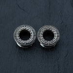 Introducing the TERA Futuristic Sci Fi Flesh Tunnels in Silver Brass by Kaya Movement, available in sizes ranging from 8mm to 20mm. These intricately designed, round metallic flesh tunnels resemble circular gears and feature detailed engravings and raised patterns on a dark, textured background. Perfect for stretched ears, they showcase a symmetrical and geometric design with a central hole—ideal for those seeking unique futuristic body jewelry.