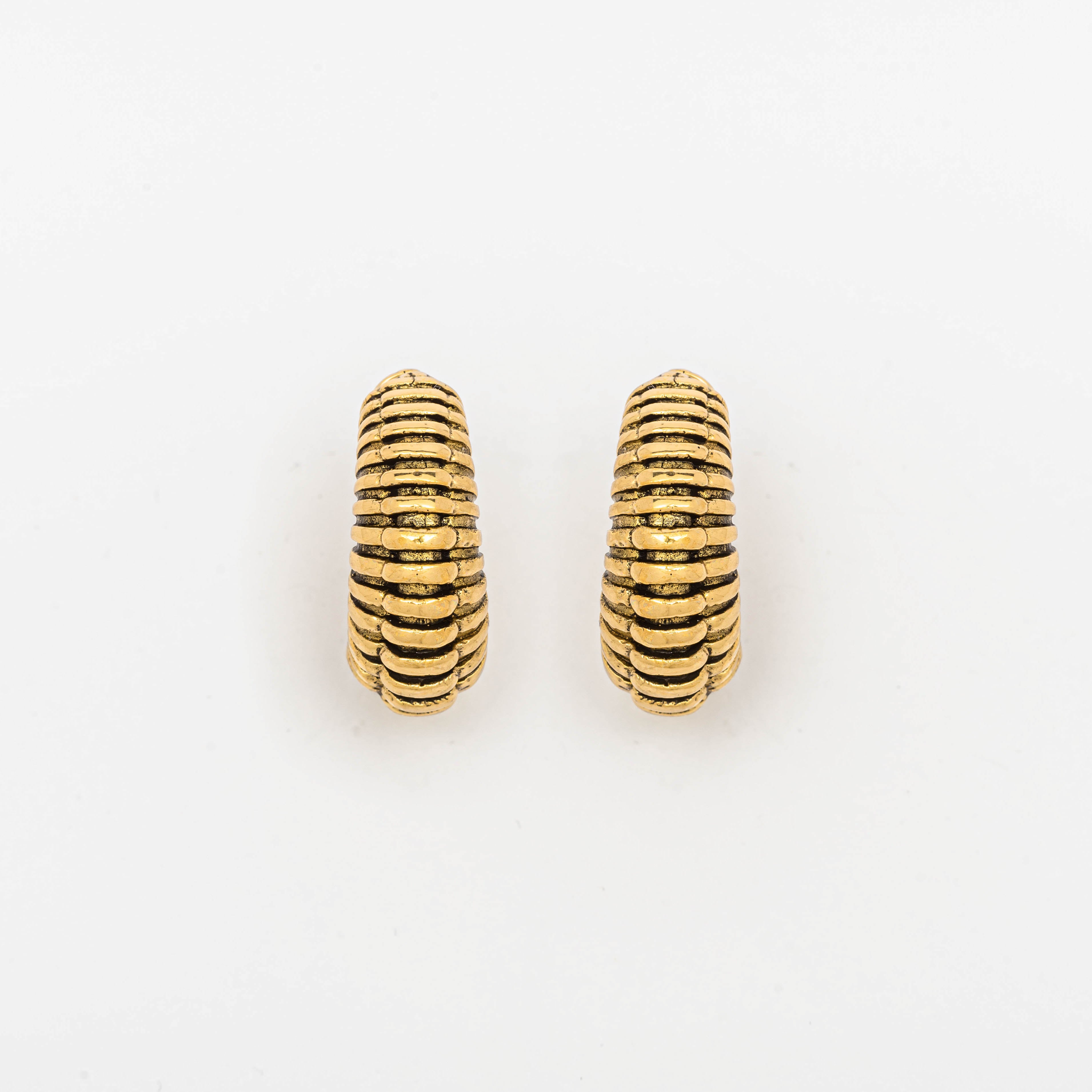 The TRILOBITE Small Biomechanical Clicker Ear Weights in Gold Brass by Kaya Movement are displayed against a white background. These earrings feature a design with multiple horizontal ridges, giving them a ribbed appearance. These stunning pieces embody the essence of post-apocalyptic body jewelry with their rugged yet refined texture.