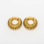 A pair of TRILOBITE Small Biomechanical Clicker Ear Weights in Gold Brass from Kaya Movement, designed with a ribbed, textured finish reminiscent of tribal gauge earrings. These circular ear weights exhibit a warm, shiny appearance and are showcased against a white background.