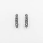 The MARVDASHT Small Biomechanical Clicker Ear Weights in 925 Silver by Kaya Movement. These unisex 2 gauge earrings boast multiple layers with a textured zigzag pattern, creating an intricately designed, geometric, and elegant look against the plain white background while evoking subtle sci-fi vibes.