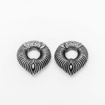 A pair of intricately designed, round MARVDASHT Medium Cyborg Clicker Ear Weights in 925 Silver by Kaya Movement against a plain white background. The ear weights feature a detailed pattern resembling feathers or leaves with a symmetrical, flowing design. Their craftsmanship gives an impression of elegance and sophistication with a touch of futuristic allure.