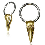Kaya Movement's CROW SKULL Gothic Silver Rings, available in 18, 16, or 14 gauge, each feature a small and intricate gold-tone brass raven skull pendant shaped like a bird's skull. These detailed pendants include beaks and eye sockets and are attached to larger silver-tone 316L surgical steel rings. The rings are presented on a white background.