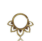 The KAAL Lotus Ring in Gold by Kaya Movement is a 20 gauge, gold-colored circular nose ring with an open edge, adorned with a tribal ethnic sunburst design featuring six petal-shaped extensions and small dot accents. This versatile piercing is showcased against a plain white background.