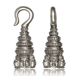 The ANGKOR WAT Heavy Ear Weights in Silver from Kaya Movement are 6 gauge ear weights with hooks that feature intricate carvings reminiscent of temple architecture, including Buddha faces at the base. These silver white brass ornaments have multiple tiers and manifest a traditional, artistic style reflective of tribal piercing body jewelry traditions.