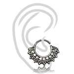 The GAE Mandala Septum Ring in Silver by Kaya Movement is an 18 gauge silver ring featuring a scalloped design adorned with small raised dots and round patterns along its edge. Crafted from 925 Sterling Silver, this simple tribal ethnic design is showcased over a faint, stylized outline of an ear on a white background.
