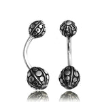 The GEO Globe Belly Piercing Ring by Kaya Movement features a pair of curved barbell piercings in silver, made from 14 gauge surgical steel. Each piece is adorned with decorative balls on both ends, showcasing intricate circular and dot patterns that add texture and ornateness. Perfect for navel jewelry, they come in elegant gift packaging.