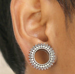 Close-up of a person's ear wearing a handcrafted TIMO Sacred Lotus Mandala Round Tunnel in silver by Kaya Movement. The plug features a decorative, beaded design around the edge, and the center is hollow, revealing the skin underneath. The ear is shown in a side profile.
