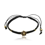 The Bracelet free size macramé nylon flower of life brass by Kaya Movement showcases an intricate bronze floral design at its center and is adorned with small gold beads. This adjustable black braided friendship bracelet features strings accented with gold beads at the ends, all set against a white background.