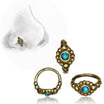 Three golden brass nose rings from Kaya Movement, named the SHA Beaded Flower Nose Ring in Gold & Turquoise, with ornate designs and natural blue turquoise gemstones are shown. A sketched nose in the background depicts one of these multi-use 20 gauge piercing rings positioned on it. The rings have a bohemian style with intricate detailing.