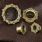 A close-up image of four LOTUS Sacred Lotus Mandala Round Tunnels in silver, created by Kaya Movement, arranged on a textured dark brown surface. The handcrafted tribal plugs vary in size from 4mm to 25mm gauge and are designed for stretched ear piercings.