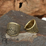 Two CIRA Beaded Ear Cuffs in Gold are displayed on a rustic stone surface. One cuff lays flat, showcasing its intricate beaded pattern, while the other stands upright, revealing its open design. The brand name "Kaya Movement" is visible in the bottom left corner.
