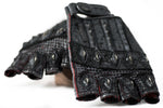 A pair of DZALA Black Genuine Leather Fingerless Gloves by Kaya Movement featuring intricate details. These custom gloves boast textured patterns, metal studs on the knuckles, and striking red accents. They are overlapping on a white background.