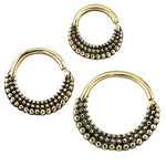 Three ISSA Seamless Septum Rings in Gold by Kaya Movement, featuring an intricate beaded tribal ethnic design. The largest ring is at the bottom right, the medium-sized ring is at the bottom left, and the smallest ring is at the top center. Each piece of this gold body jewelry showcases a textured pattern of small beads.