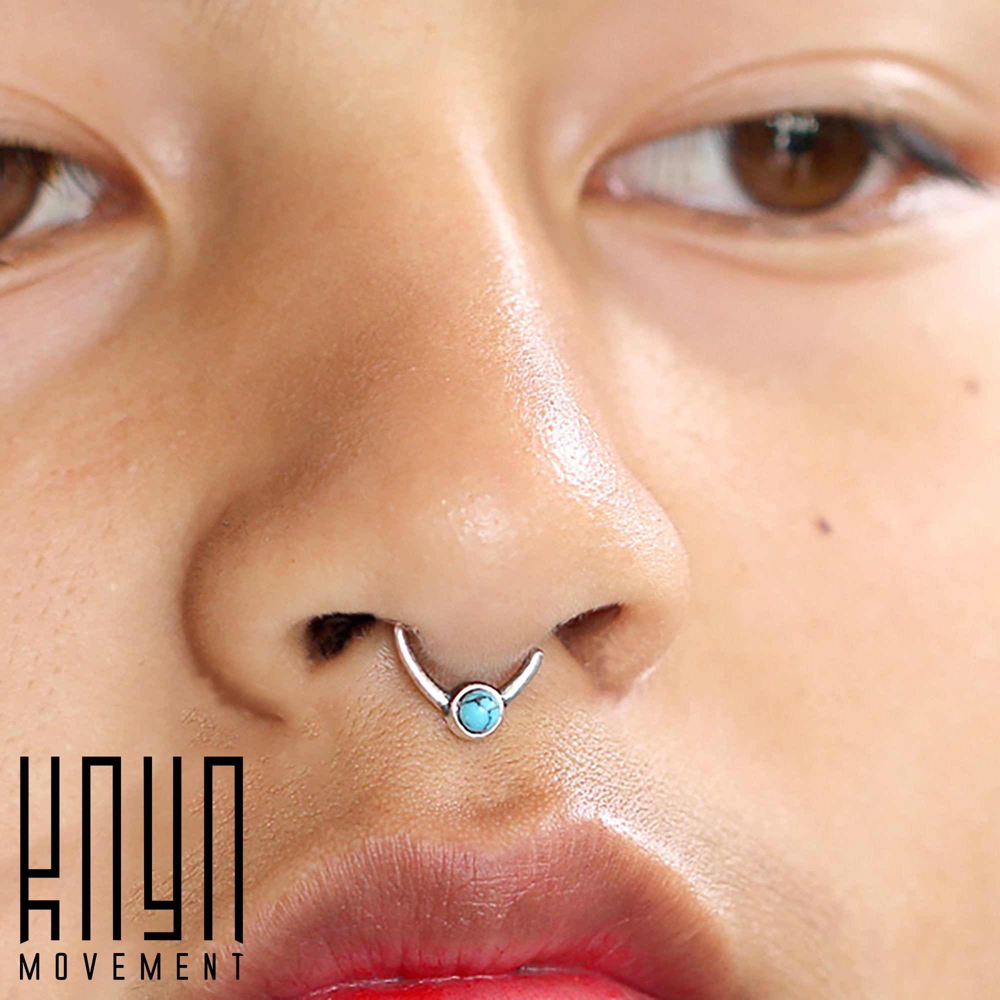 Close-up of a person with a septum piercing, featuring the NAE Seamless Septum Ring in Silver & Turquoise by Kaya Movement, crafted from 925 sterling silver and adorned with a natural blue turquoise gemstone. The person has light brown eyes and a natural skin tone. The text "Kaya Movement" is visible in the bottom-left corner.