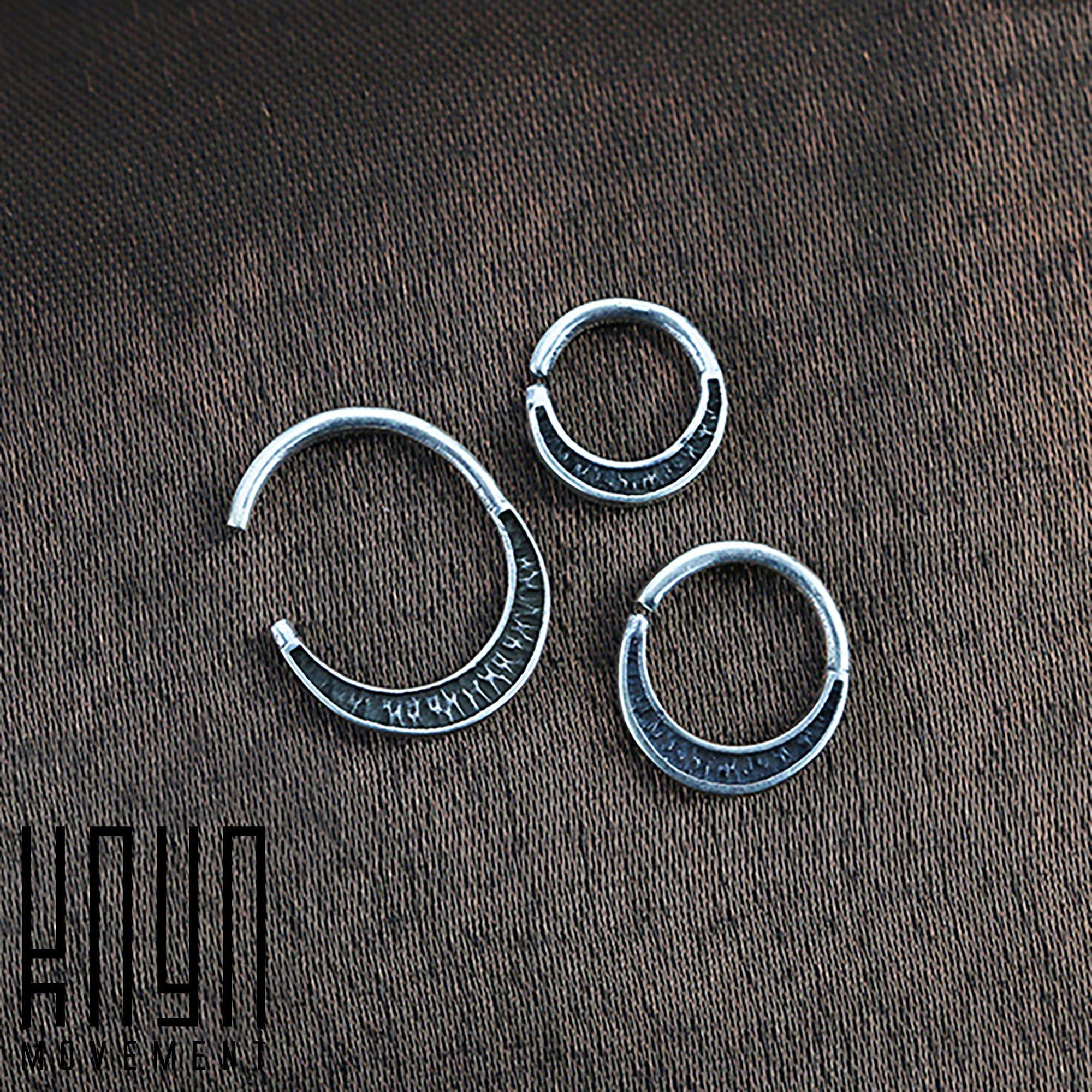 A close-up image of three Kaya Movement MOON Seamless Rings in Silver (16 gauge) of varying sizes, arranged on a textured fabric surface. Each ring has engraved markings along its outer edge. In the bottom left corner, there is a logo with stylized text.