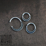 A close-up image of three Kaya Movement MOON Seamless Rings in Silver (16 gauge) of varying sizes, arranged on a textured fabric surface. Each ring has engraved markings along its outer edge. In the bottom left corner, there is a logo with stylized text.