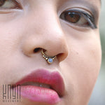 Close-up of a person's face highlighting the ANI Seamless Septum Ring in Gold & Moonstone (16 gauge). The individual is wearing pink lipstick and has black eyeliner. "Kaya Movement" is visible in the bottom left corner, emphasizing the exquisite piece of body jewelry.