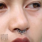 Close-up of a person wearing intricate, petal-shaped MAWAR Lotus Flower Septum Ring in Silver from Kaya Movement. The image focuses on the nose and part of the lips. The person's smooth skin contrasts beautifully with the decorative details of the 18 gauge silver septum ring. The logo "Kaya Movement" is visible in the bottom left corner.