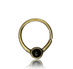 Discover the "NAE" by Kaya Movement - an elegant nose ring featuring a simple, sleek design. This ethnic septum jewelry showcases a single black onyx gemstone at the bottom center, set in a small, smooth bezel. The handmade 18g (1mm) gold band is open-ended and does not form a complete circle, adding to its unique appeal.