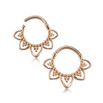 The MAWAR Lotus Clicker Septum Ring in Rose Gold by Kaya Movement features a design reminiscent of a pair of body jewelry hoop earrings, with intricate petal-shaped extensions at the bottom. Small spherical accents adorn each petal, lending these 16-gauge hoops an elegant and decorative appearance. The septum ring includes a hinged clasp for secure closure.
