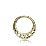 The AYM Seamless Septum Ring in Gold by Kaya Movement is an 18 gauge circular earring showcasing a series of alternating triangular cutouts along its bottom half. The design is simple yet elegant, with a reflective surface highlighting its metallic sheen, embodying the essence of tribal design.