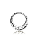 A close-up image of the AYM Seamless Septum Ring in Silver by Kaya Movement showcases a circular, 925 sterling silver earring with a hinge clasp. The lower half features a row of small, evenly spaced triangular cutout designs, making this reflective and polished 18 gauge piece perfect for versatile silver body jewelry.