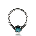 Introducing the NAE Seamless Septum Ring in Silver & Turquoise by Kaya Movement. This 18 gauge septum ring showcases an open design with a single round natural blue turquoise gemstone centrally set. Crafted from 925 sterling silver, the ring features a smooth finish and securely encloses the vibrant gemstone. Its minimalist style and adjustable nature make it a versatile piece of body jewelry suitable for any occasion.