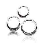 Three MOON Seamless Rings from Kaya Movement, crafted from 925 Sterling Silver and available in a 16 gauge size, are displayed against a white background. The crescent-shaped body jewelry rings feature a textured surface on the inner arc, showcasing simple yet elegant design details. The reflection of the rings is subtly visible below them.