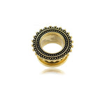 A 19mm gold gauge from Kaya Movement's Flesh Tunnel piercing collection, featuring a circular tribal design with a decorative border of small black and gold dots and intricate beaded detailing around the edge.